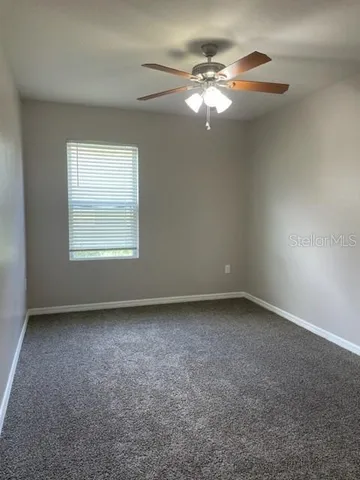 an empty room with windows and fan