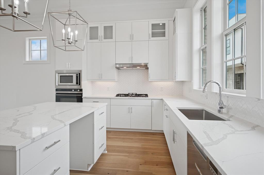 Kitchen with backsplash, plenty of natural light, glass insert cabinets, and white cabinets