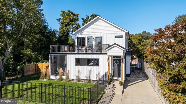 a view of a white house with large trees and couches chairs