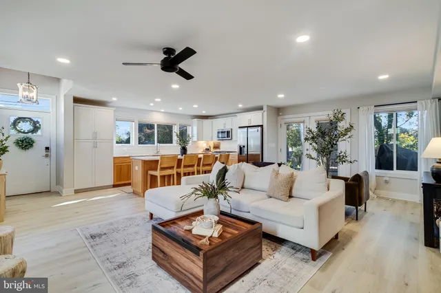 a living room with furniture kitchen view and a large window