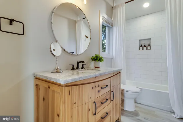 a bathroom with a granite countertop sink a toilet and a mirror