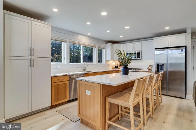 a kitchen with stainless steel appliances granite countertop a refrigerator a sink dishwasher a stove and a refrigerator with wooden floor