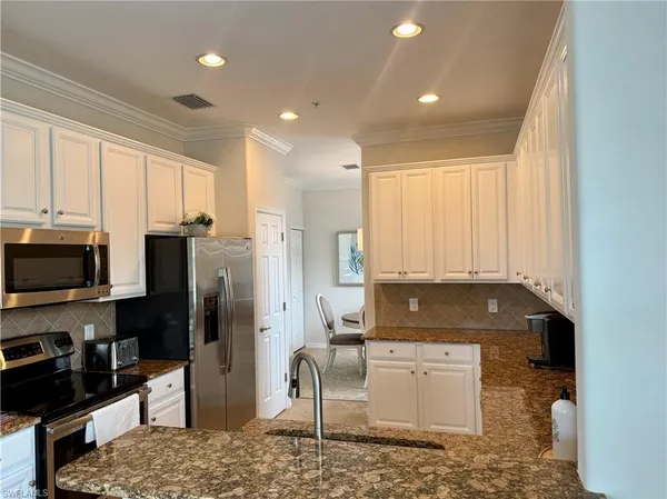 a kitchen with stainless steel appliances granite countertop a stove a refrigerator and a sink