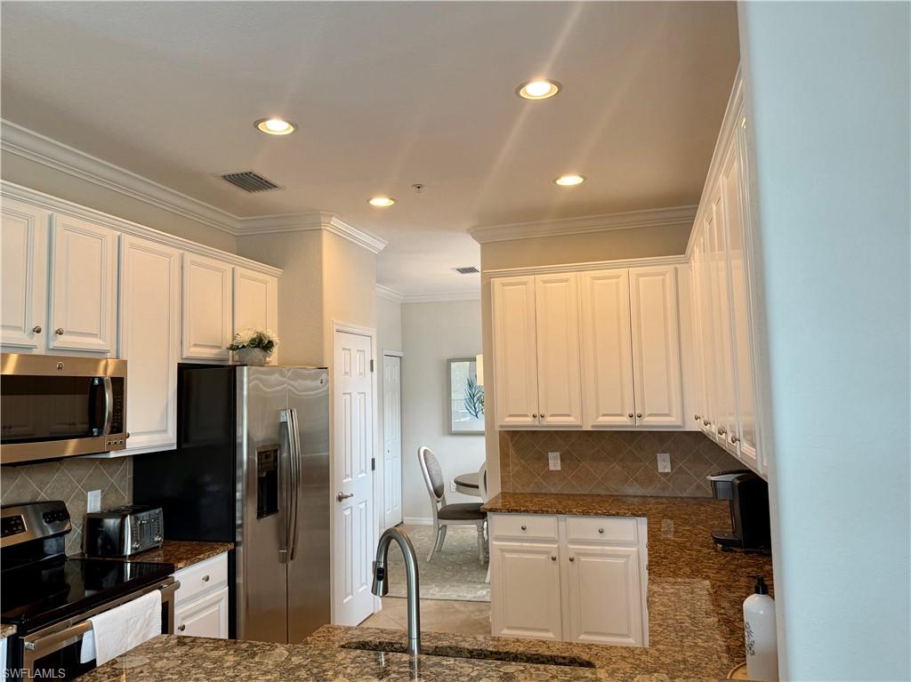 9498 Napoli Lane, Unit 201 Naples, FL 34113 - Photo 15 of 48 a kitchen with stainless steel appliances granite countertop a refrigerator a stove and a sink with wooden floor