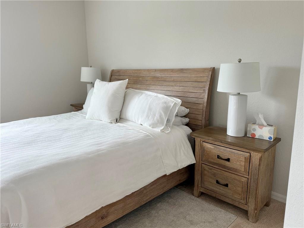 9498 Napoli Lane, Unit 201 Naples, FL 34113 - Photo 33 of 48 a bedroom with a bed and a lamp on the dresser
