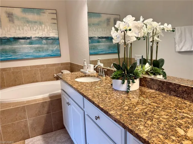 a bathroom with a granite countertop sink a large mirror and bathtub