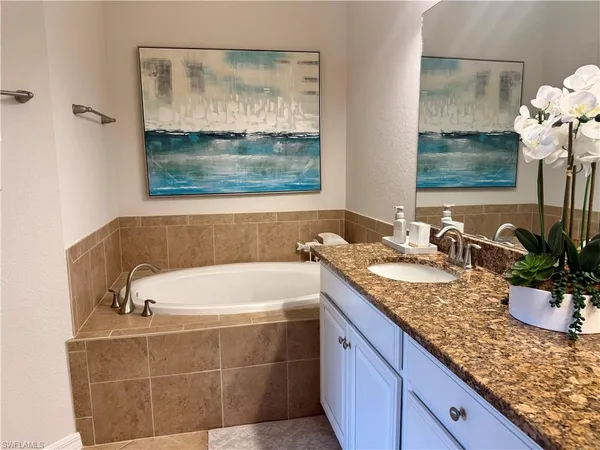 a bathroom with a granite countertop tub a sink and mirror