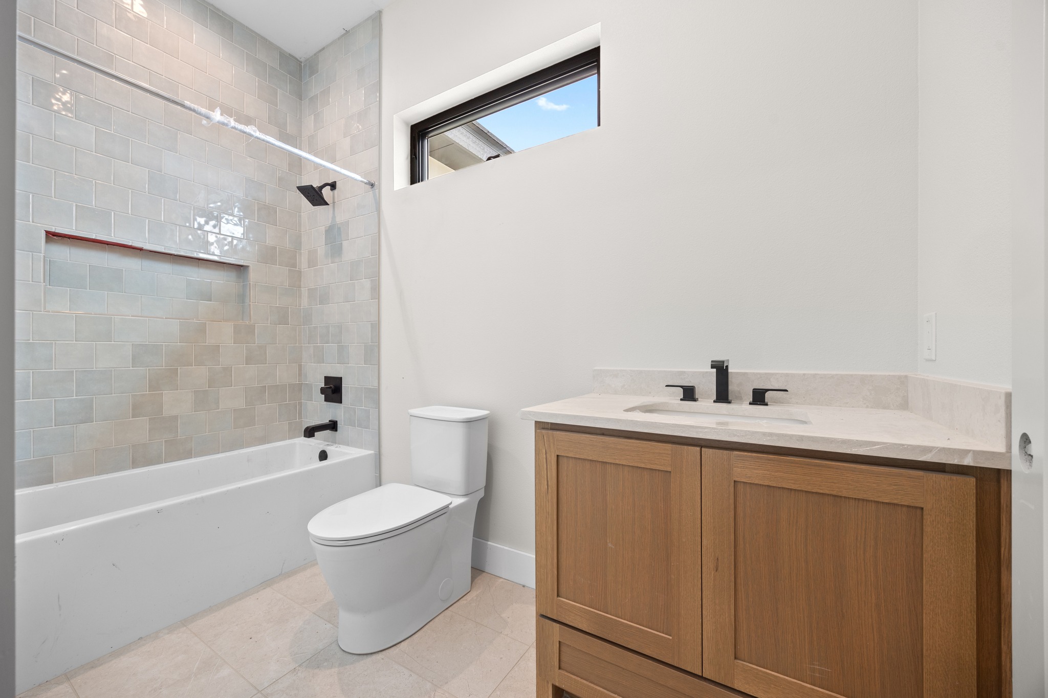 903 Flint Ridge Trail Georgetown, TX 78628 - Photo 30 of 39 Bathroom featuring a white bathtub with subway tile surround, integrated shower niche, and matte black fixtures