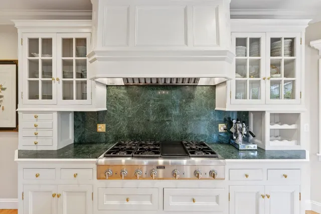 a kitchen with kitchen island granite countertop a stove top oven a sink a dining table and chairs