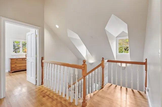 a spacious bedroom with a bed a mirror and a large window with wooden floor