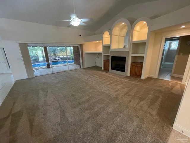 a view of an empty room with a fireplace and a window