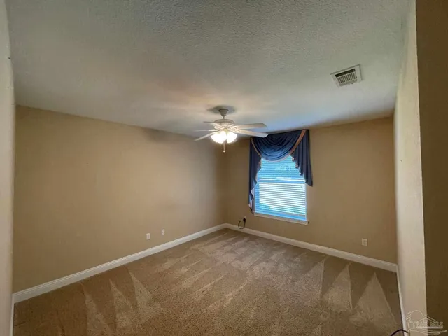 an empty room with a chandelier fan and windows