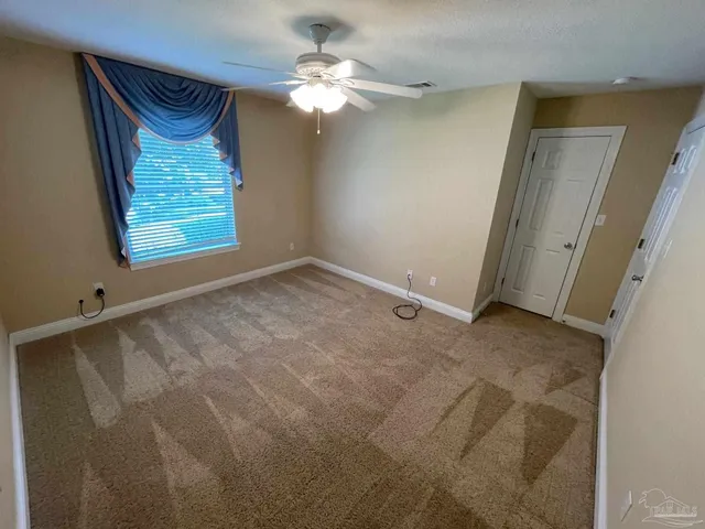 a view of a bedroom with a chandelier fan and a window