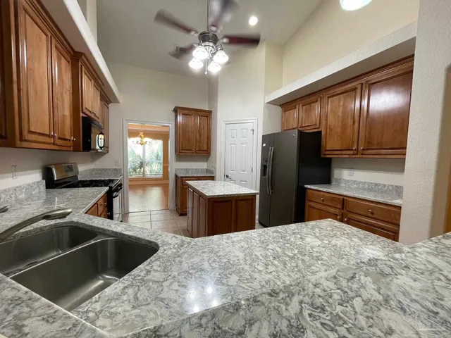 a kitchen with stainless steel appliances kitchen island granite countertop a sink refrigerator and microwave