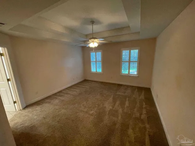 en empty room with windows and ceiling fan