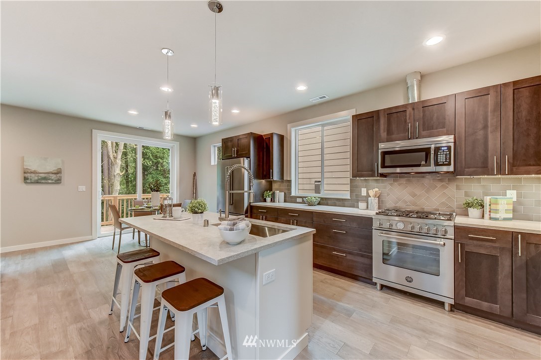 22827 23rd Avenue Southeast, Unit 7 Bothell, WA 98021 - Photo 3 of 19 a kitchen with stainless steel appliances granite countertop a stove top oven a sink dishwasher a dining table and chairs with wooden floor