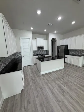 a large kitchen with stainless steel appliances a large counter top a stove and a wooden floors