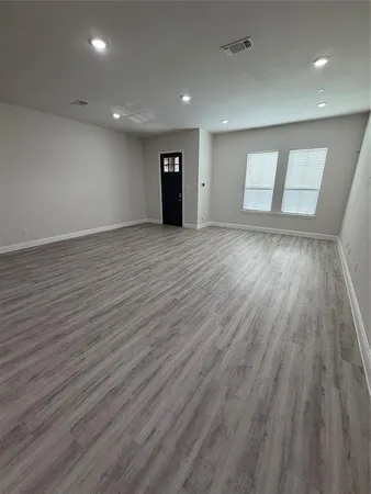 a view of an empty room with wooden floor and window