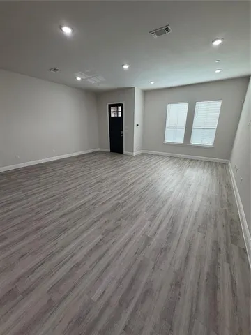 a view of an empty room with wooden floor and window