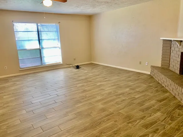 an empty room with a fireplace and wooden floor