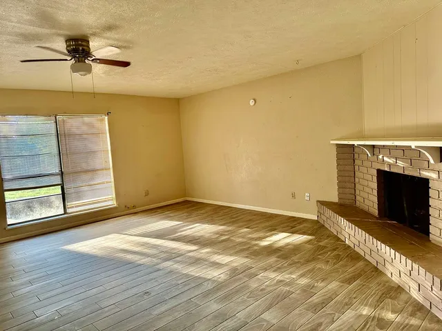 a view of empty room with a fireplace and wooden floor