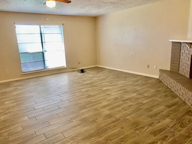 a view of an empty room with a fireplace and a chandelier fan
