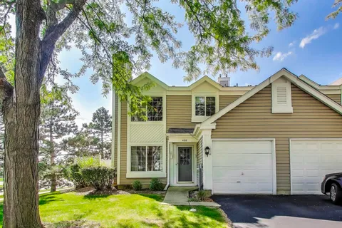 a view of a white house next to a yard with big trees