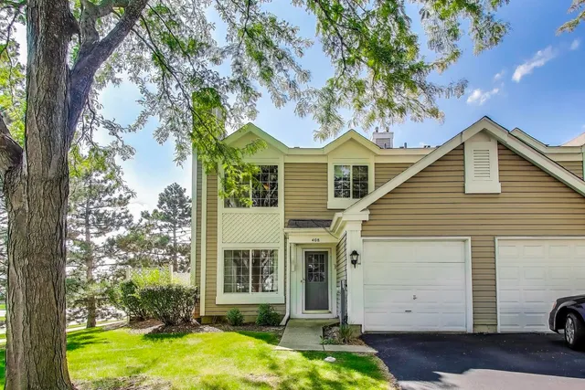 a view of a white house next to a yard with big trees
