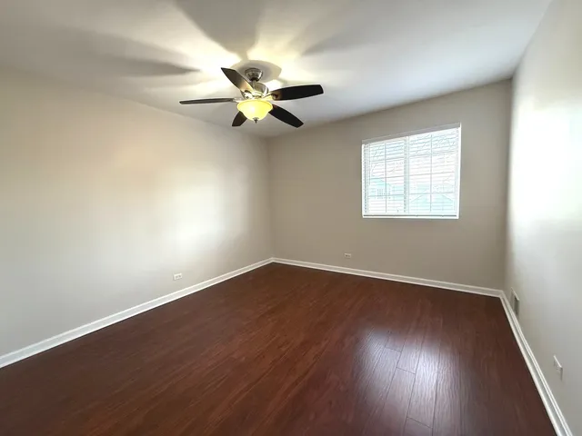 an empty room with wooden floor fan and windows