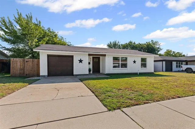 a front view of house with yard and trees in the background