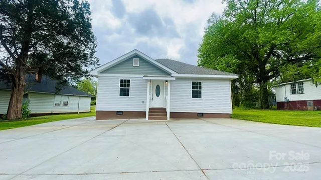 a view of a house with a yard and large tree