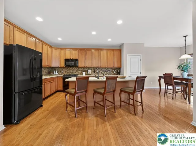 a kitchen with stainless steel appliances a dining table chairs stove refrigerator and cabinets