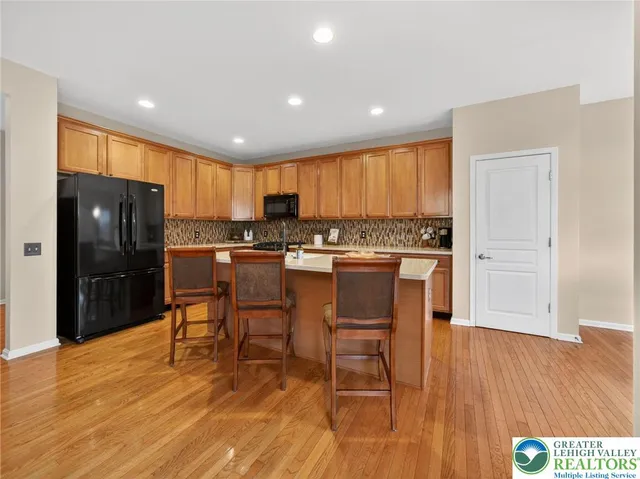 a kitchen with stainless steel appliances granite countertop a stove a refrigerator a sink a dining table and chairs with wooden floor