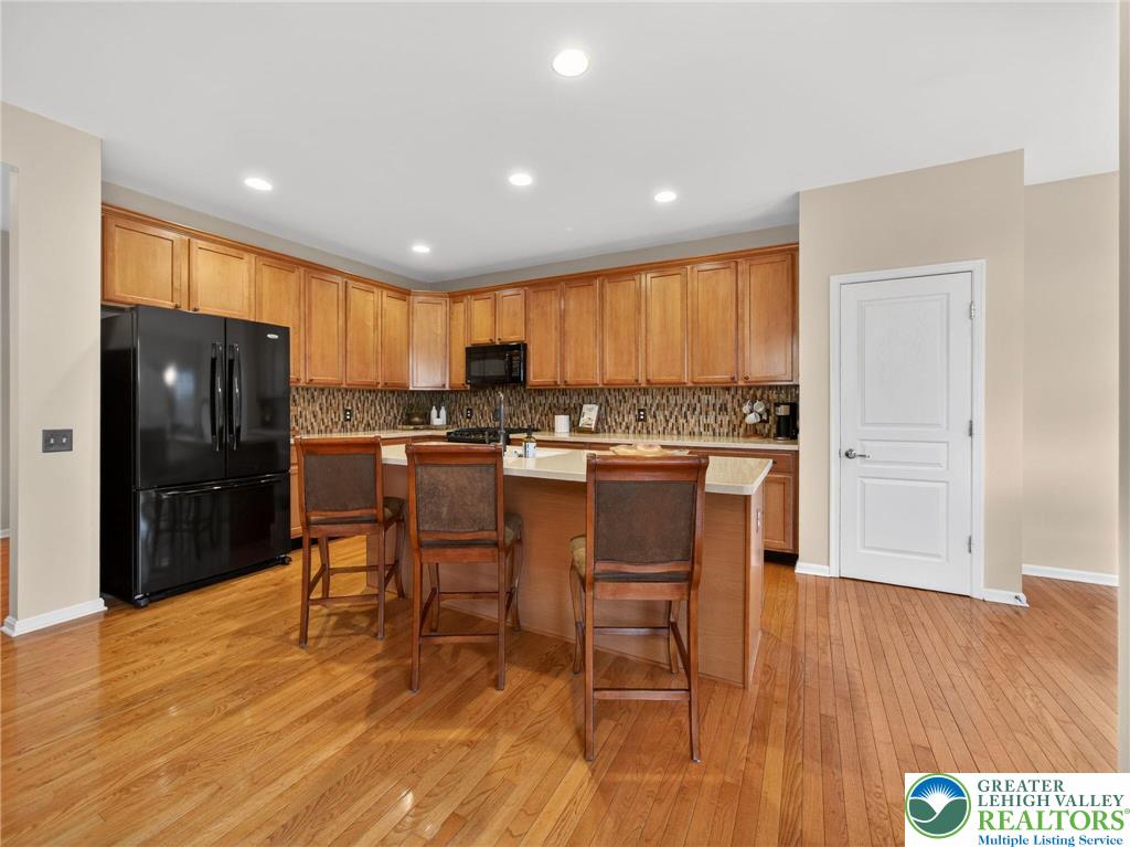 8611 Cascade Road Breinigsville, PA 18031 - Photo 20 of 40 a kitchen with stainless steel appliances granite countertop a stove a refrigerator a sink a dining table and chairs with wooden floor