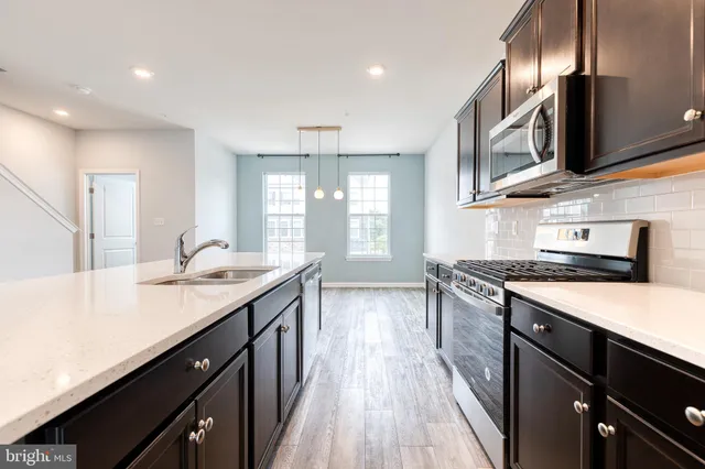 a kitchen with stainless steel appliances granite countertop a sink a stove and a wooden floors