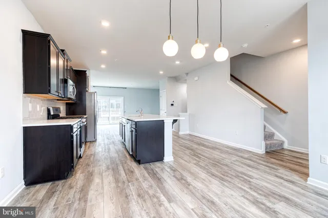 a kitchen with stainless steel appliances kitchen island granite countertop a stove top oven a sink a counter space and cabinets