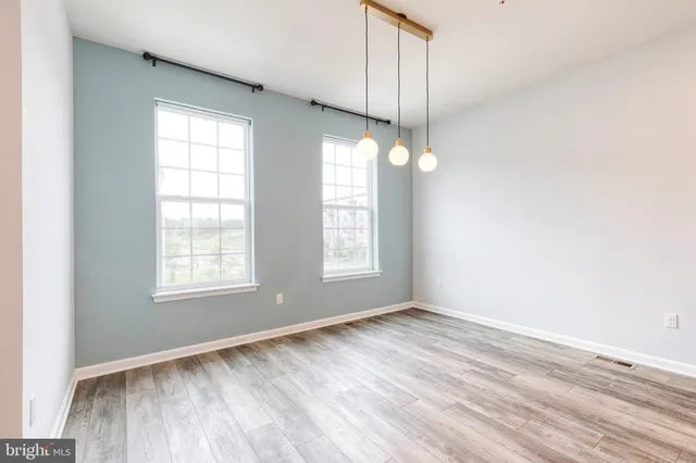 an empty room with wooden floor fan and windows
