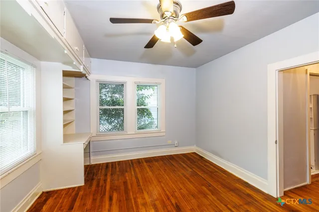 a view of empty room with wooden floor and fan