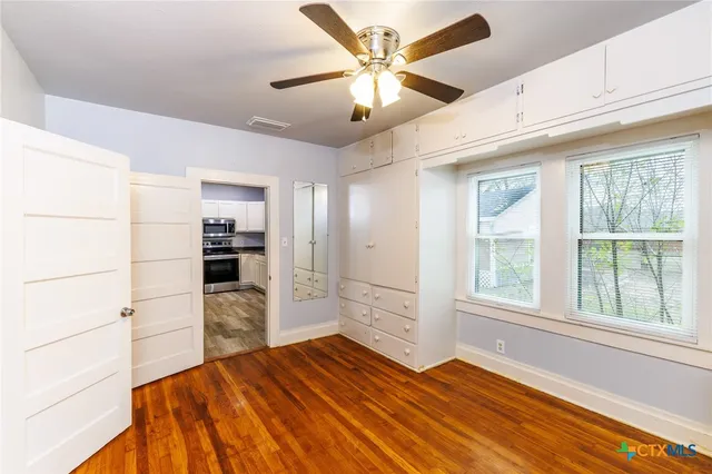 a bedroom with a bed and a large window with wooden floor