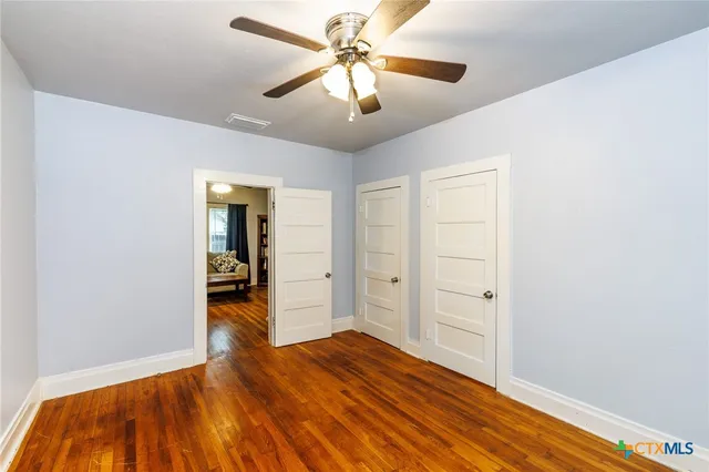 a view of a room with wooden floor and ceiling fan