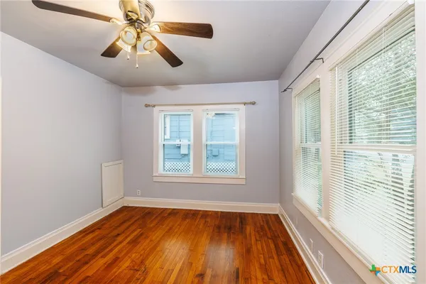 a view of an empty room with wooden floor and a window