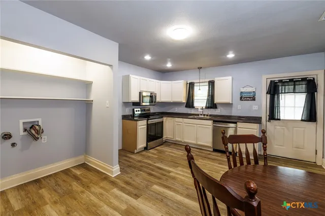 a kitchen with granite countertop stainless steel appliances refrigerator sink dining table and chairs