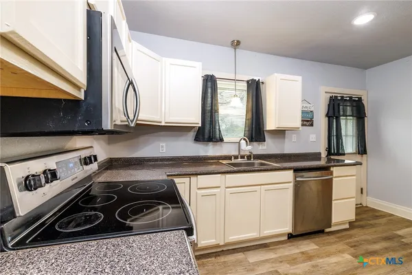 a kitchen with stainless steel appliances a sink a stove and cabinets