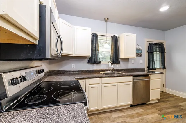 a kitchen with stainless steel appliances a sink a stove and cabinets