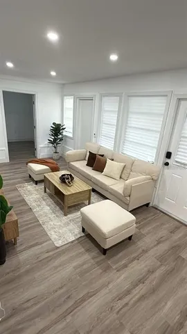 a living room with couches and kitchen view with wooden floor