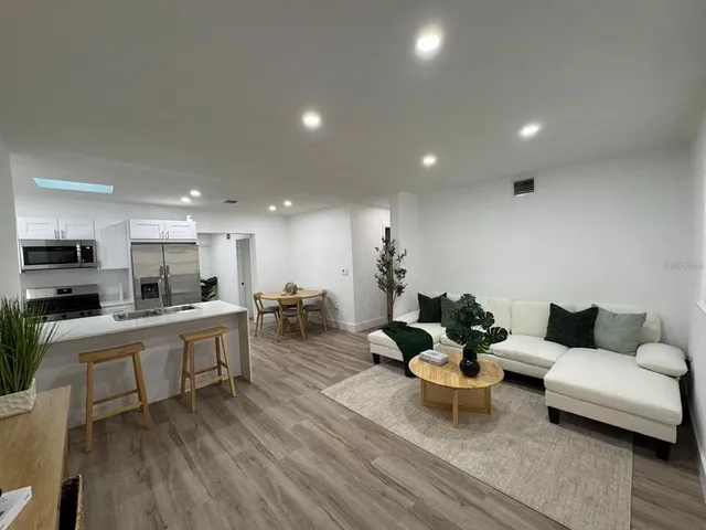 a living room with furniture kitchen view and a wooden floor