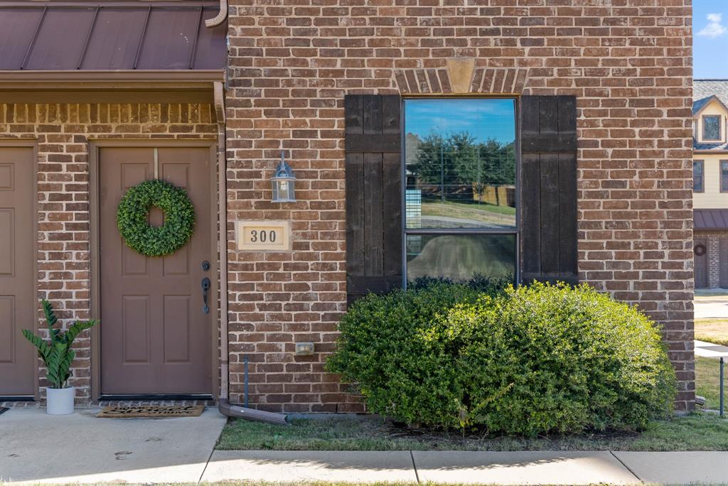11118 Marion Road, Unit 105 Sanger, TX 76266 - Photo 5 of 29 Brick facade featuring a panel door, decorative window shutters, and a prominent house number plaque