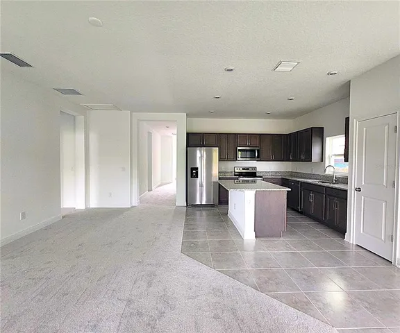 a large kitchen with stainless steel appliances granite countertop a stove top oven a sink and a refrigerator