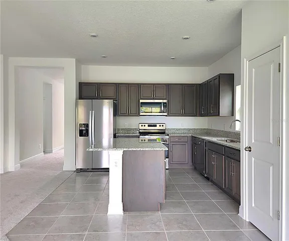 a kitchen with stainless steel appliances granite countertop a refrigerator and a stove top oven