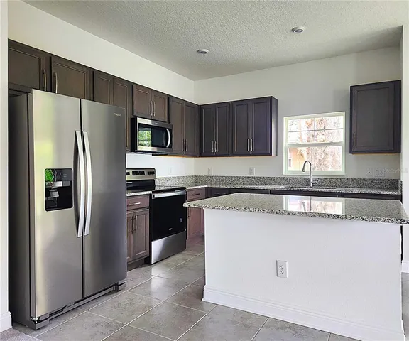 a kitchen with stainless steel appliances granite countertop a refrigerator stove a sink and dishwasher
